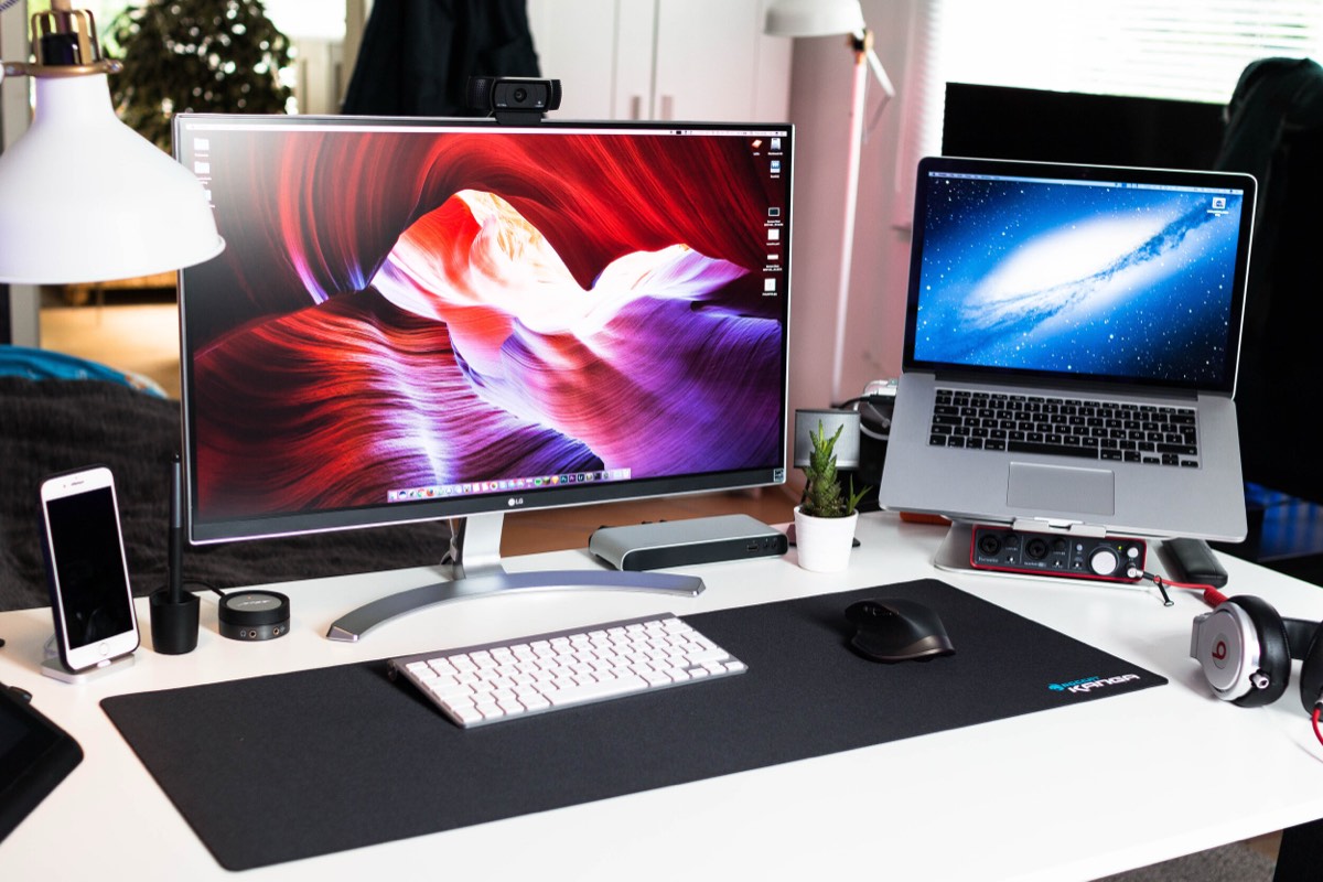 A home workspace with a desktop monitor, laptop and phone
